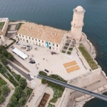 Vue aérienne du fort près de la mer avec des terrains de pétanque.