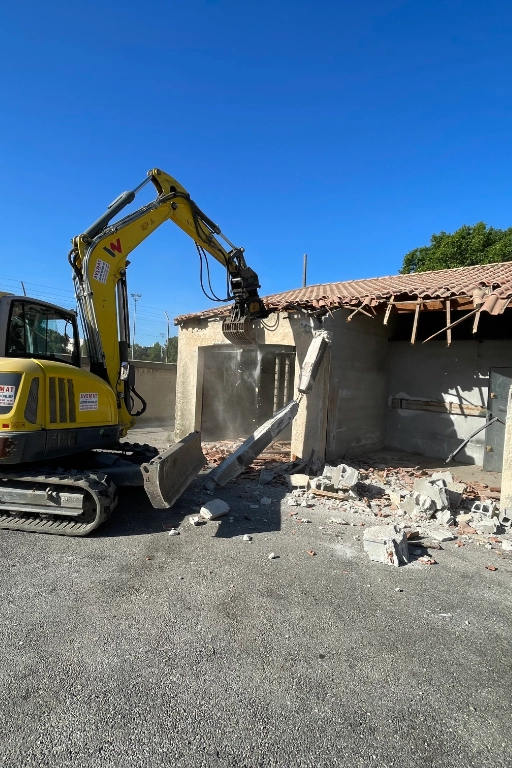 Mini-pelle démolissant un bâtiment en béton.