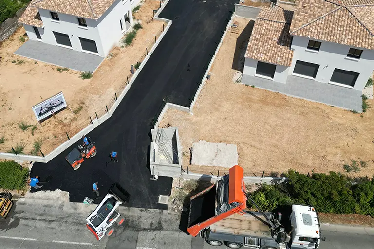 Route en construction devant des maisons neuves.