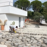 Ouvrier posant des pavés marseillais devant maison moderne