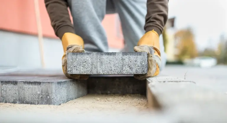 solutions-vrd-viabilisation-raccordements-et-parking Pavés en chantier avec niveau et marteau.