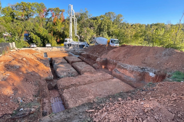 Chantier de construction avec bétonnière et fondations creusées.