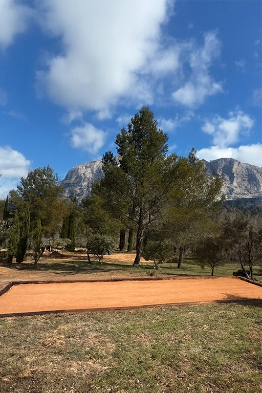 creation-terrain-petanque-traverses-bois-aix-en-provence Terrain de pétanque devant montagnes sous ciel bleu.
