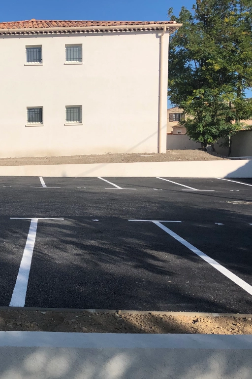 Parking vide devant bâtiment beige ensoleillé
